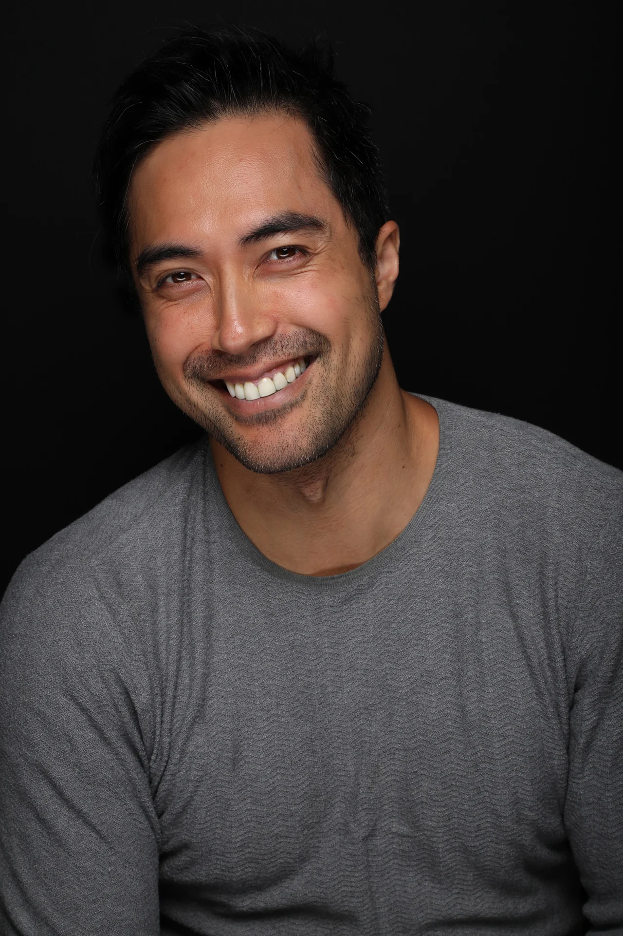 Damien Sato smiling in a relaxed portrait